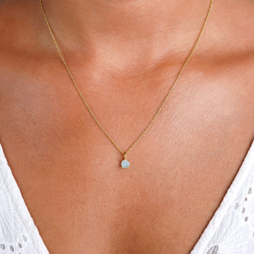 Gold necklace with small crystal charm in Aquamarine. Crystal necklace with a stylish aquamarine charm that has a blue color.