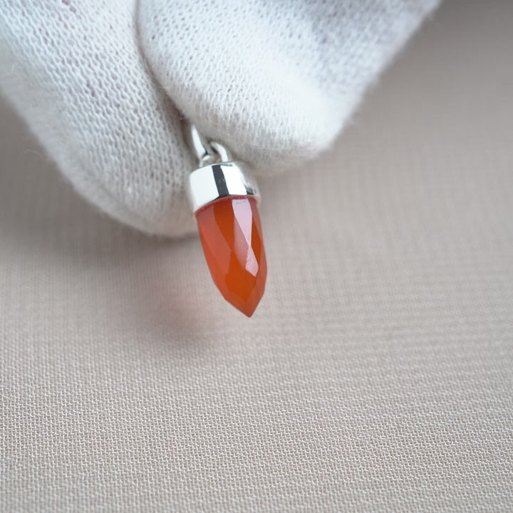 Carnelian shaped into a small point with silver details. Gemstone jewelry pendant with Carnelian in silver.