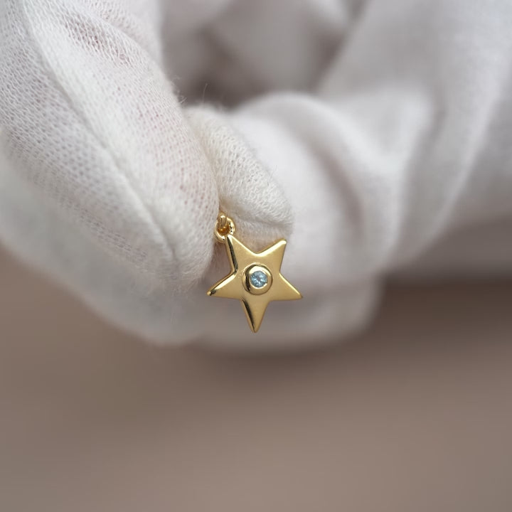 Gemstone charm with a star in gold and a small Blue Topaz crystal. Birthstone jewelry with a star in gold an a tiny Blue Topaz crystal.