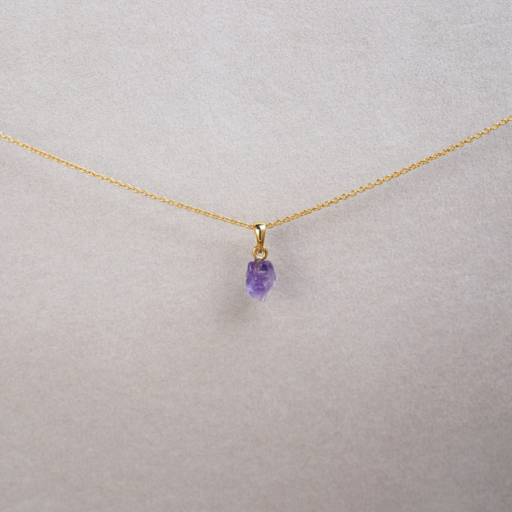 Gold necklace with a small raw purple gemstone Amethyst. Necklace in gold with an Amethyst charm. 