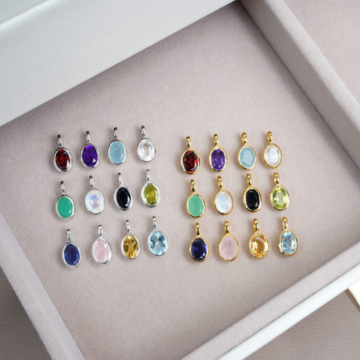 Birthstone pendants with different gemstones in silver and gold. Crystal jewelry with birthstones.