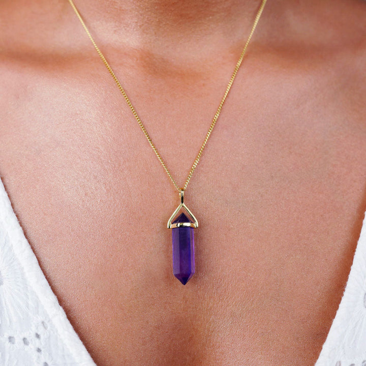 Amethyst necklace in the form of a point with gold details. Jewelery with purple gemstone Amethyst which is the birthstone of February.