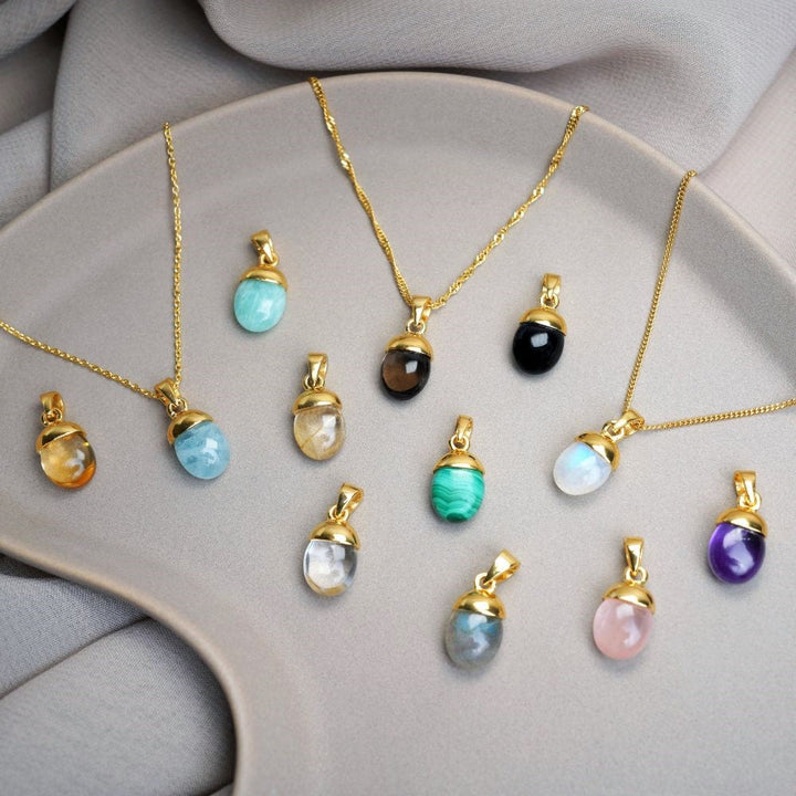 Gemstone jewelry with tumbled crystals in magical colors. Crystal jewelry with colorful gemstone pendants in gold.