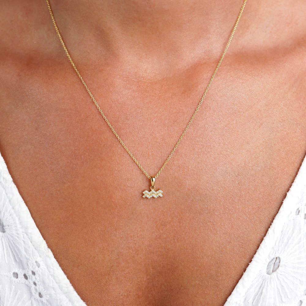 Gold necklace with Aquarius (Water Bearer) charm with White Topaz crystals. Zodiac necklace in gold.